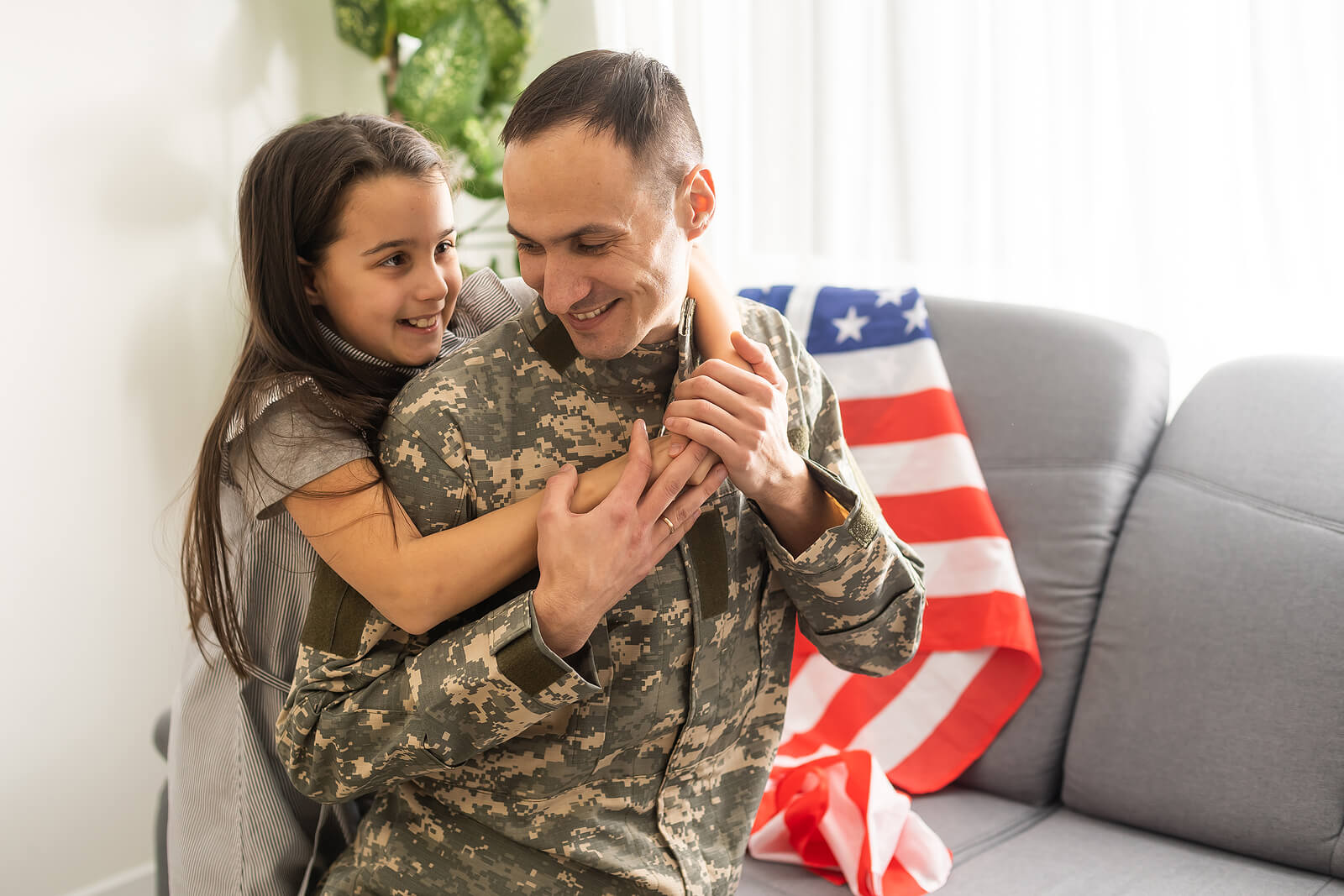 Child hugs man in military uniform
